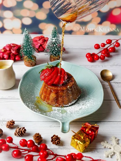 A festive Christmas pudding with syrup being poured, styled with seasonal props to create a warm, holiday mood.