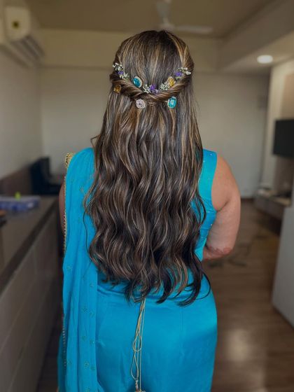 A half-updo with a braided crown, decorated with beautiful gemstone clips. This adds a unique and colorful touch to a wavy hairstyle for a Mehendi look.