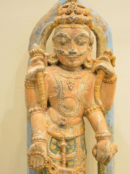 A painted wooden sculpture of Chaturbhuja Indra, the King of the Gods. His four arms hold symbols of power, embodying his role as the protector of the East. This is a fine example of traditional South Indian divinity sculpture.