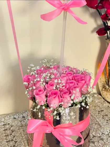 The base of our hot air balloon arrangement, showcasing a dense cluster of beautiful pink roses and delicate baby's breath nestled in a reflective silver box with a matching pink bow.
