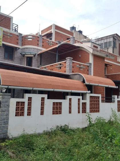 The gentle curve of the roof provides both aesthetic appeal and functional benefits, reducing heat gain. The facade uses a mix of stone, brick, and jaali walls.