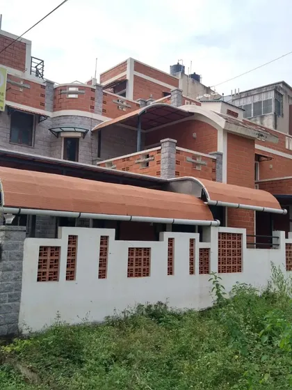 The gentle curve of the roof provides both aesthetic appeal and functional benefits, reducing heat gain. The facade uses a mix of stone, brick, and jaali walls.