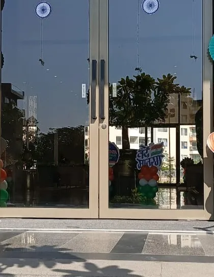 The entrance to this building is decorated with tricolor balloon pillars topped with hot-air-balloon-themed cutouts. The green paper fan decorations add another layer of texture to the Republic Day setup.