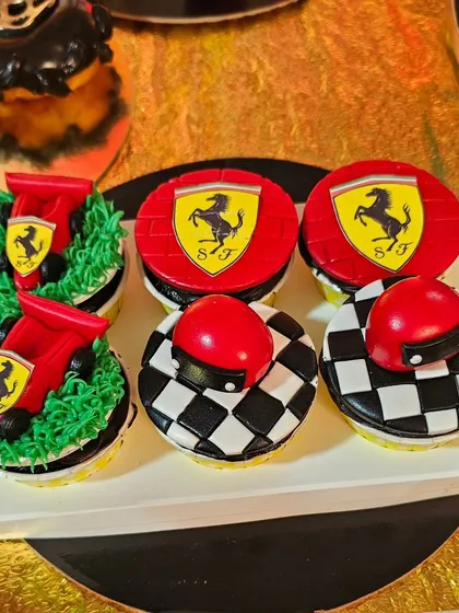 Ferrari-themed cupcakes with checkered flags, helmets, and the iconic logo, part of a racing-themed dessert table.