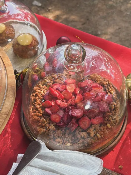 A beautiful strawberry crumble tart displayed under a glass dome at my stall at Sunder Nursery. I love seeing people's reactions when they try my desserts.