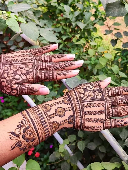 This party henna design features intricate geometric bands on the wrist and fingers.