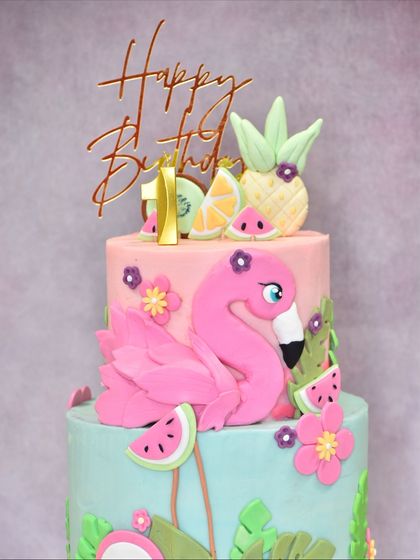 Another angle of the two-tiered flamingo cake, showing the full composition of the flamingo, tropical fruits, and flowers.