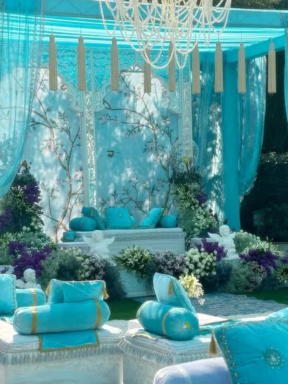 A wider view of the turquoise-themed seating area. The combination of plush cushions, flowing drapes, and a custom chandelier with hanging tassels creates a look of relaxed luxury.