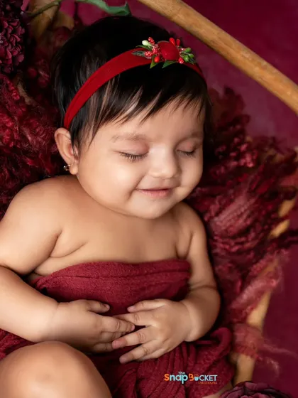 A sweet, sleeping baby girl. This portrait captures the peaceful and angelic nature of a 4-month-old, wrapped cozily in red.