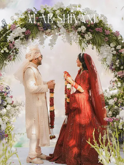 A wide shot of the couple during their jaimala under a beautiful floral arch.