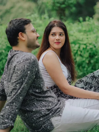 A quiet moment in the park. Jayashree and Anand, in coordinated black and white traditional outfits, share a look during their serene outdoor pre-wedding shoot.