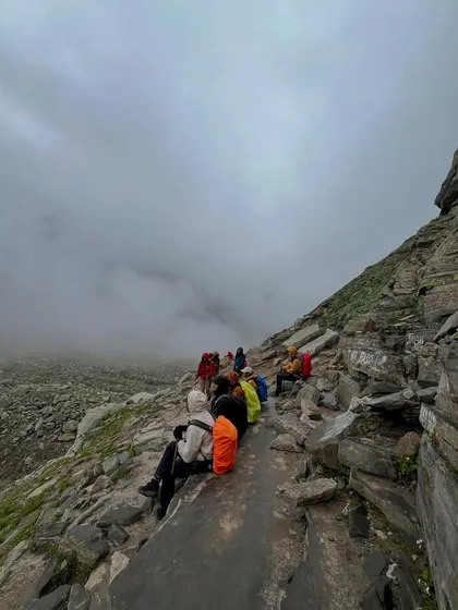 A moment of rest on the rocky ascent to Hampta Pass, with clouds rolling in below.