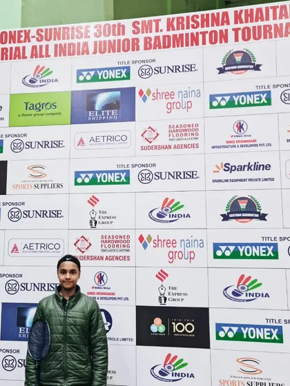 Our player Sneha stands before the official banner of the Yonex-Sunrise All India Junior Badminton Tournament. Her performance earned her a spot among the top 32 players in the main draw.