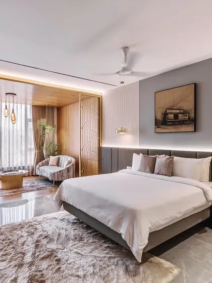This hotel room interior is an exercise in refined comfort. We used a combination of fluted wall panels, warm wood, and custom art deco-inspired screens to create a distinct seating area within the room, making the space feel more like a personal suite.