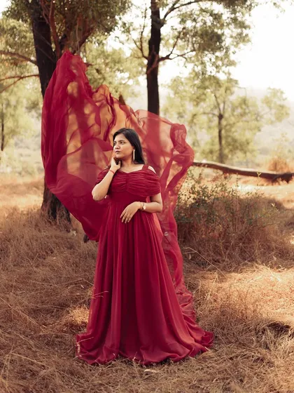Let the fabric do the talking. This vibrant red infinity gown with a flying train adds a pop of color and incredible movement to your photos, creating a truly unforgettable and dramatic maternity portrait.
