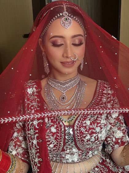 A minimalist bride's dream. This look features soft, rosy eyeshadow and diamond jewelry, creating a modern and fresh take on the classic red bridal lehenga.