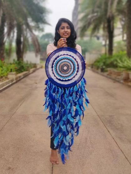 A full view of one of us holding the giant evil eye dreamcatcher. Its size makes it a commanding and protective presence in any room.