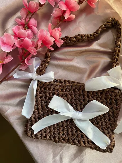 A detailed product shot of the brown ribbon bag. You can see the chunky crochet texture and the soft satin ribbons I use.