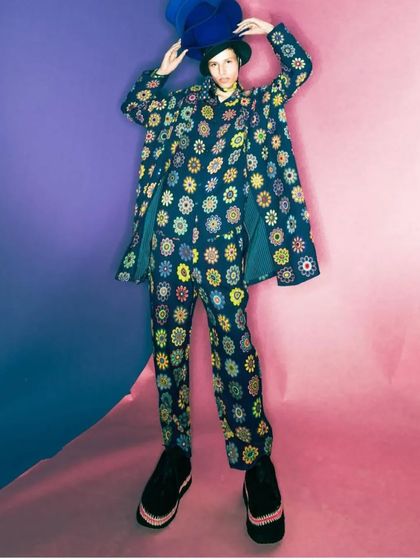 This studio shot from a fashion campaign features a model in a vibrant floral suit. I styled the hair to be simple and contained under the hat, allowing the colorful outfit and bold pattern to be the main focus.