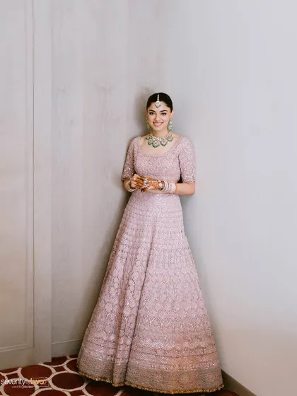 A full-length portrait of the bride, her smile radiant, looking elegant and poised in her beautiful pink lehenga.