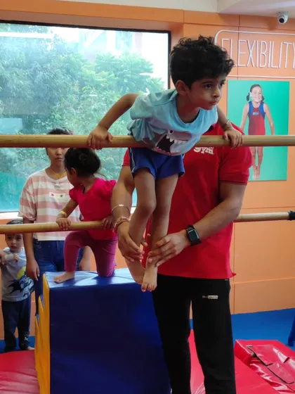 This little one shows great focus while practicing on the bars with a coach's help. These activities are excellent for developing upper body strength and grip.