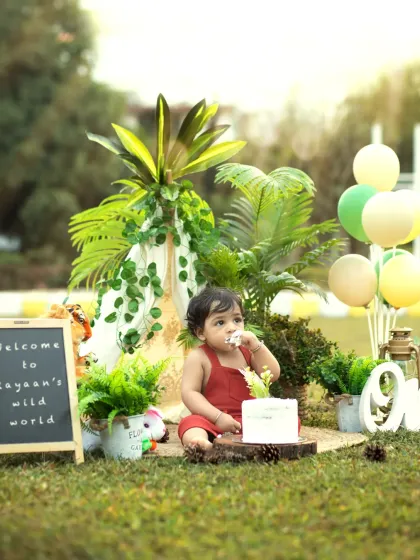 A wide shot showing the full jungle-themed setup in a park. The teepee, plants, and balloons create a perfect backdrop for a wild one's birthday.