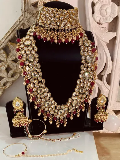 The complete red and gold Kundan bridal set, available for rent. It includes the choker, long necklace, jhumka earrings, passa, and nath.