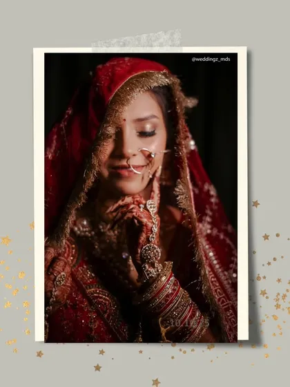 A shy, beautiful bride captured in a moment of quiet reflection, her face partially covered by her red bridal dupatta.