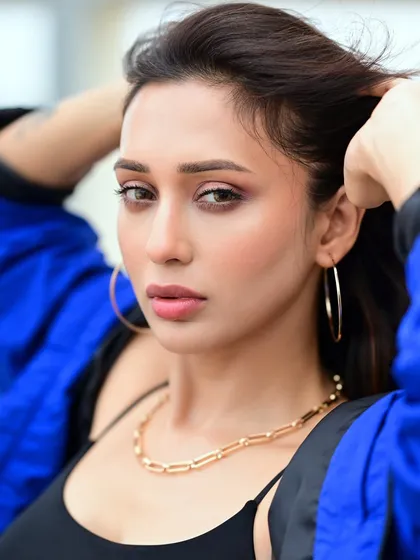 A beauty shot of Mimi, with her hands brushing through her hair. The focus is on her flawless makeup and the modern, gold-chain necklace.