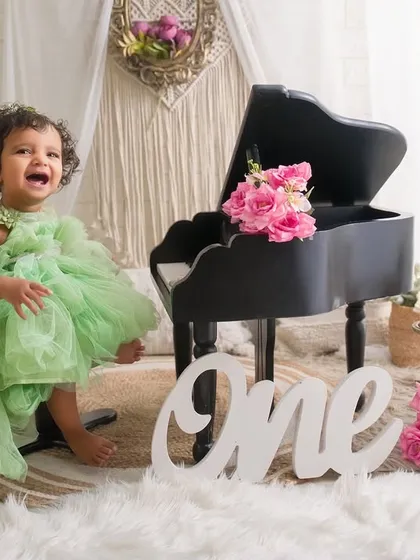 Twirling into her first birthday with the biggest smile. This photo captures the pure, energetic joy of a one-year-old in a beautiful, light-filled studio setting.