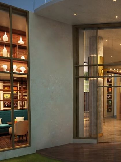 An exterior view looking into the M3M Golf Estate cafe. The design ensures the inviting atmosphere is visible from the outside, with large windows showcasing the warm interior and elegant decor.