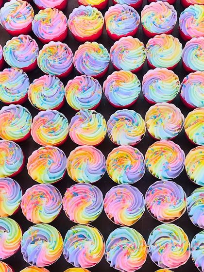 A large order of our rainbow cupcakes, neatly arranged and ready to be delivered. We take great care in preparing every single one.