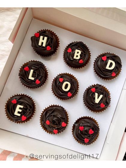 A still shot of the 'HBD LOVE' double chocolate cupcakes, decorated with little red hearts.
