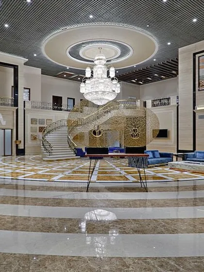 The A-Class Marble showroom is organized into four distinct zones, including this grand reception area. A massive, three-tiered glass chandelier provides verticality, while the concentric circles of the marble floor guide visitors through the space.