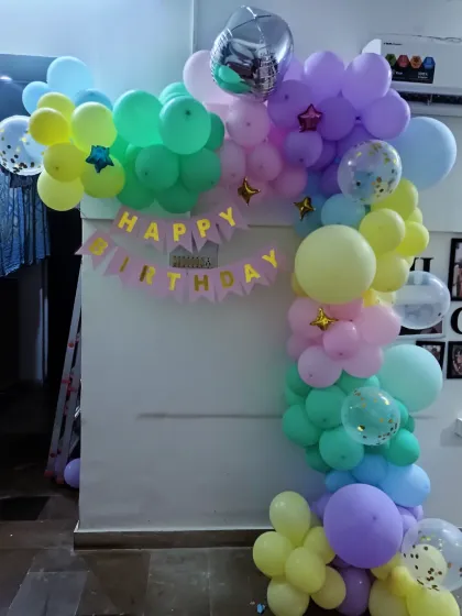 A cheerful and colorful pastel balloon arch inside a home. This is a great way to create a photo corner or decorate an entryway for a birthday surprise.