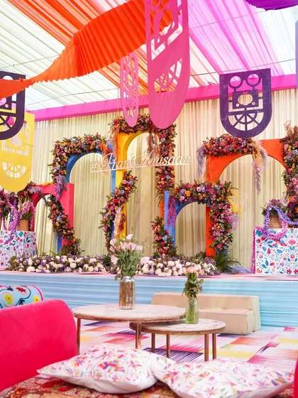 A view of the Haldi stage from a guest's perspective, showing the vibrant seating and the colorful, flower-adorned stage in the background. The entire space is designed to feel like a joyous carnival.