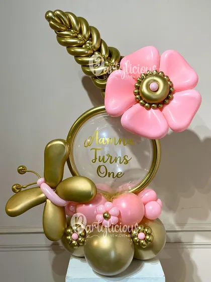 A truly artistic and personalized balloon bouquet for a first birthday. This creation features a golden butterfly, a pink balloon flower, and a custom message, all crafted with intricate detail.