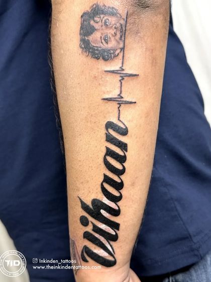 This cover-up tattoo transforms an old piece into a heartfelt tribute to a son. It features his portrait, name, and a heartbeat line, symbolizing that he is forever in his father's heart.