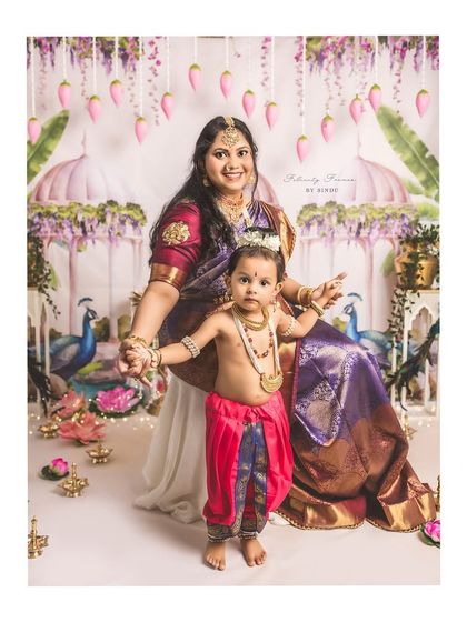 A mother dressed as Yashoda holds the hands of her son, dressed as little Krishna. This themed portrait beautifully captures a divine and eternal love story.