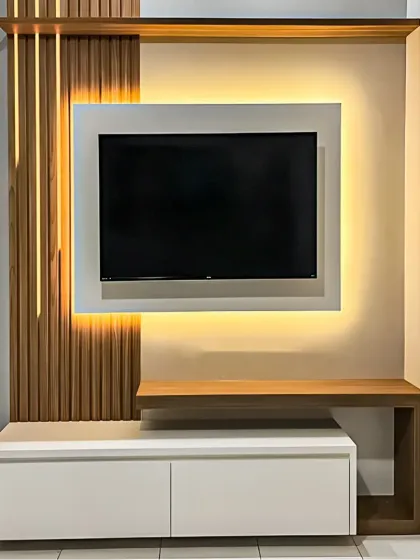 This compact TV unit design uses asymmetrical elements and integrated backlighting to create visual interest in a smaller space. The combination of a white floating console and a wood-look bench provides both storage and a display surface.