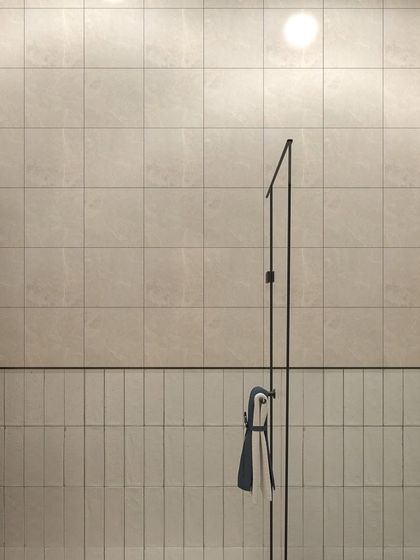 This view shows the clean and simple design of the shower area. The combination of vertical and horizontal tiles adds subtle texture, while the glass partition keeps the space feeling open and bright.