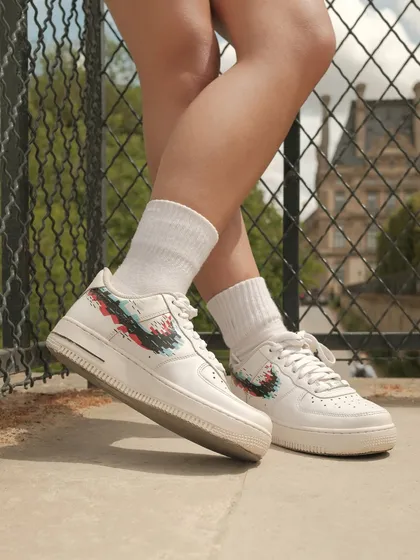 A lifestyle shot from Paris showing the custom glitch-effect Nike swoosh sneakers being worn, proving my designs are made for walking.