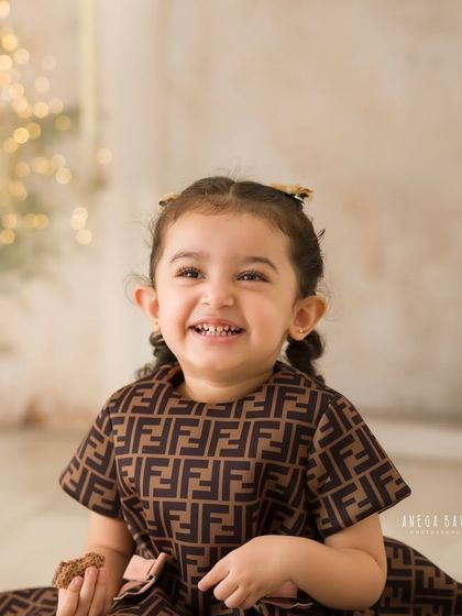 A beautiful, happy portrait of a little girl with a radiant smile. The soft lighting and warm background create a lovely, timeless feel.