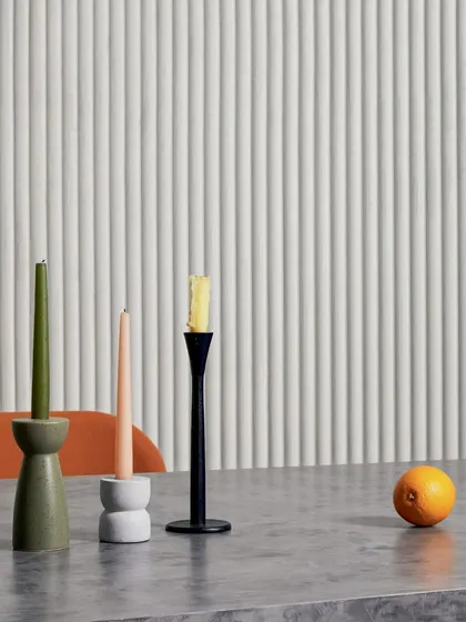 A minimalist dining setup is enhanced by a white, vertically ribbed 3D wallcovering. The design adds texture and a sense of height to the space, creating a serene and elegant atmosphere.