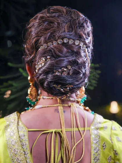 This textured bridal bun is all about elegance and detail. Adorned with golden leaf accessories, it creates a regal and sophisticated look for a wedding reception or sangeet night.