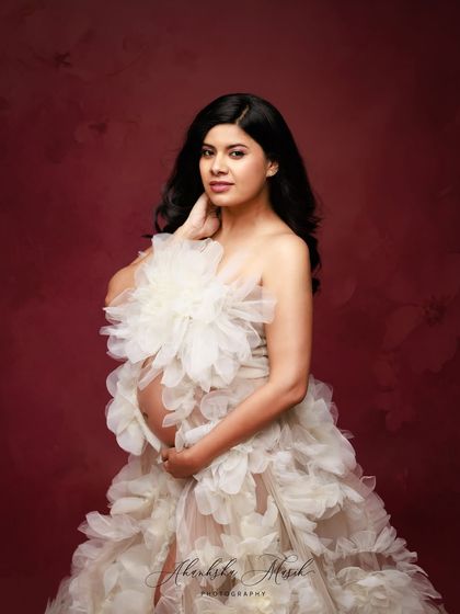 This unique gown, adorned with large, soft fabric flowers, creates a beautiful texture and a truly artistic statement for a maternity portrait.