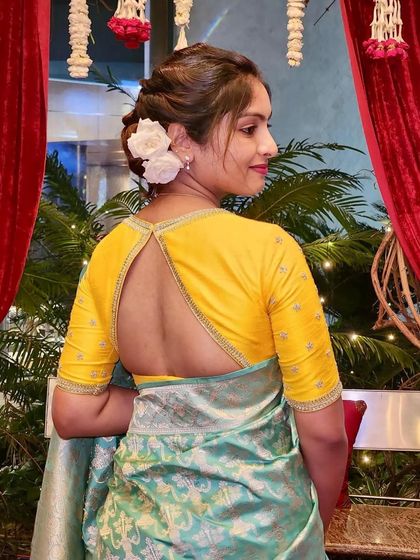 A client wearing a yellow blouse with a keyhole back, paired with a light green printed saree for a fresh, summery look.