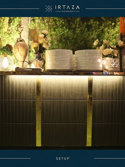 A beautifully lit serving counter with neatly stacked plates, ready for guests to begin their culinary journey. The under-counter lighting adds a modern, chic touch.