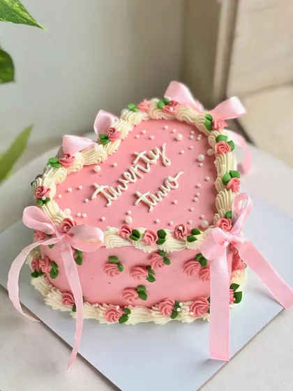 Turning twenty-two never looked this pretty. This vintage-inspired heart cake is full of delicate details, from tiny buttercream roses and pearls to soft satin bows, serving main character energy for your special day. 🌸