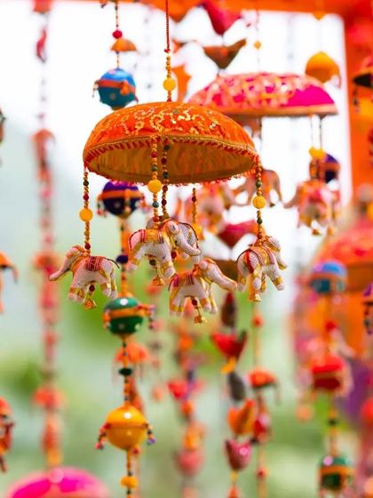 We used traditional Rajasthani decor elements, like these colorful hanging umbrellas and elephant tassels, to create an authentic and festive atmosphere for this Mehendi celebration.
